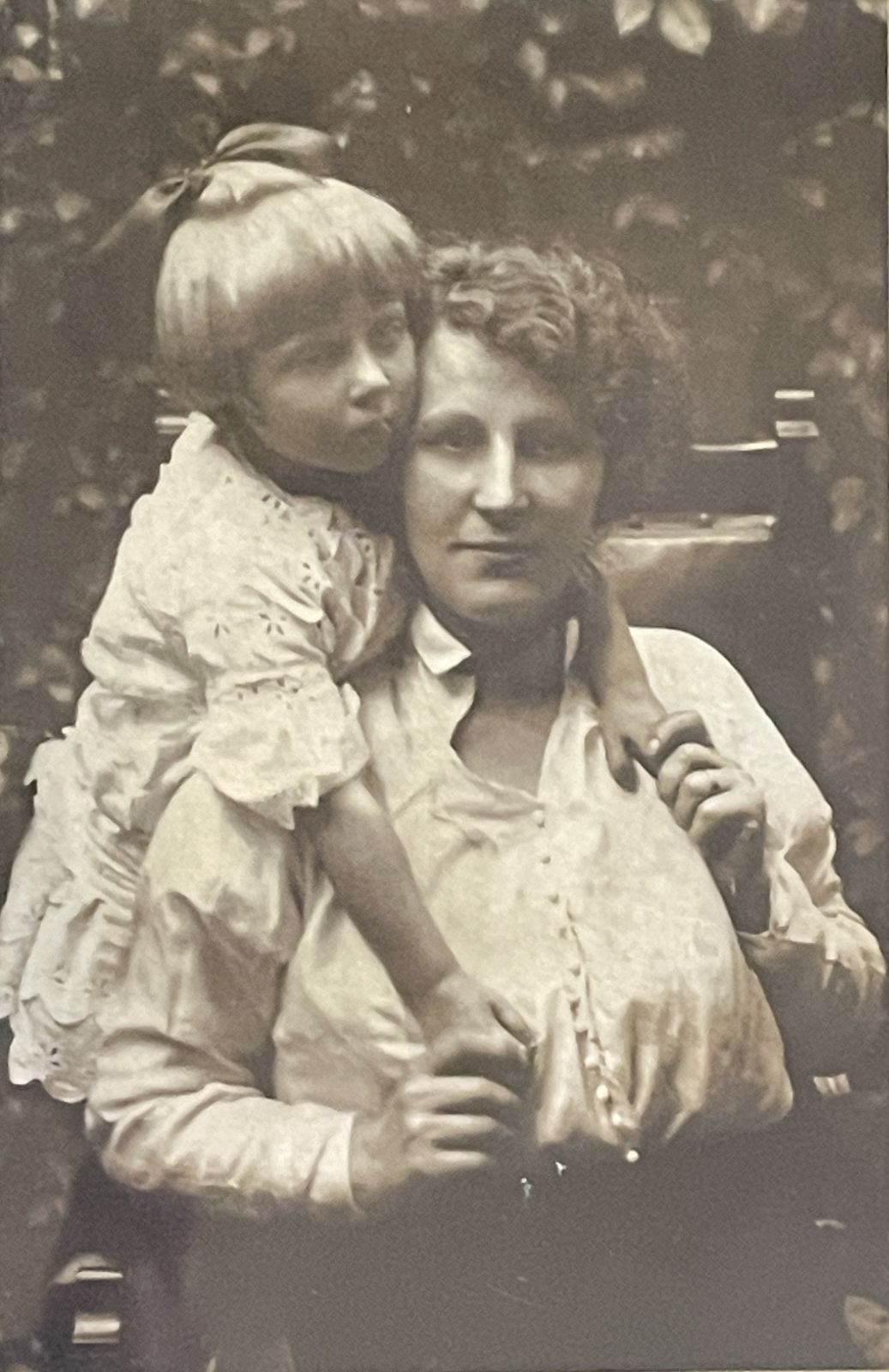 Dora seated with one of her young daughters as a toddler on her lap.
